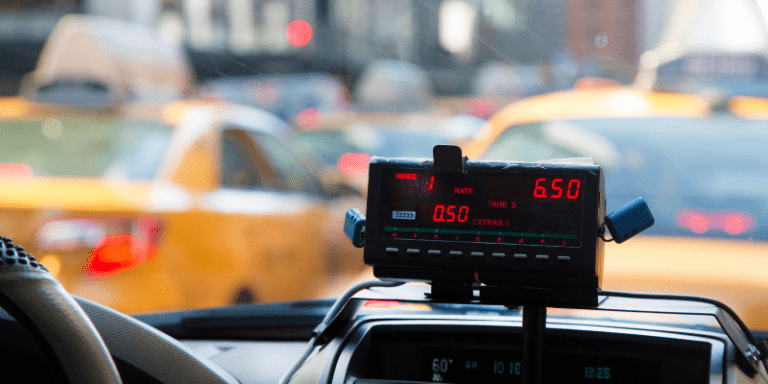 Pantalla de taxímetro mostrando tarifas en un taxi en Barcelona, destacando el costo del servicio en medio del tráfico urbano.