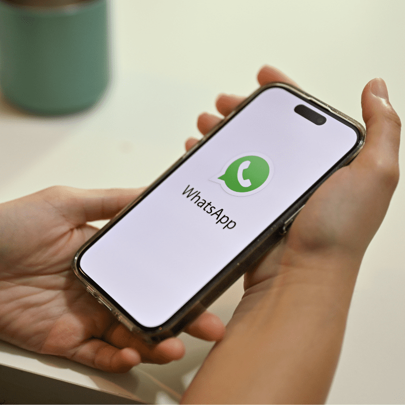 Persona sosteniendo un teléfono móvil con la aplicación de WhatsApp abierta, facilitando la opción de reservar un taxi en Barcelona de manera rápida y cómoda.