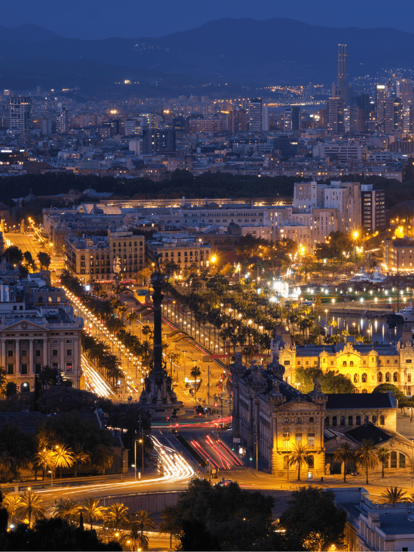 Taxi Tour Barcelona con vista nocturna del puerto y la ciudad, destacando puntos turísticos emblemáticos.